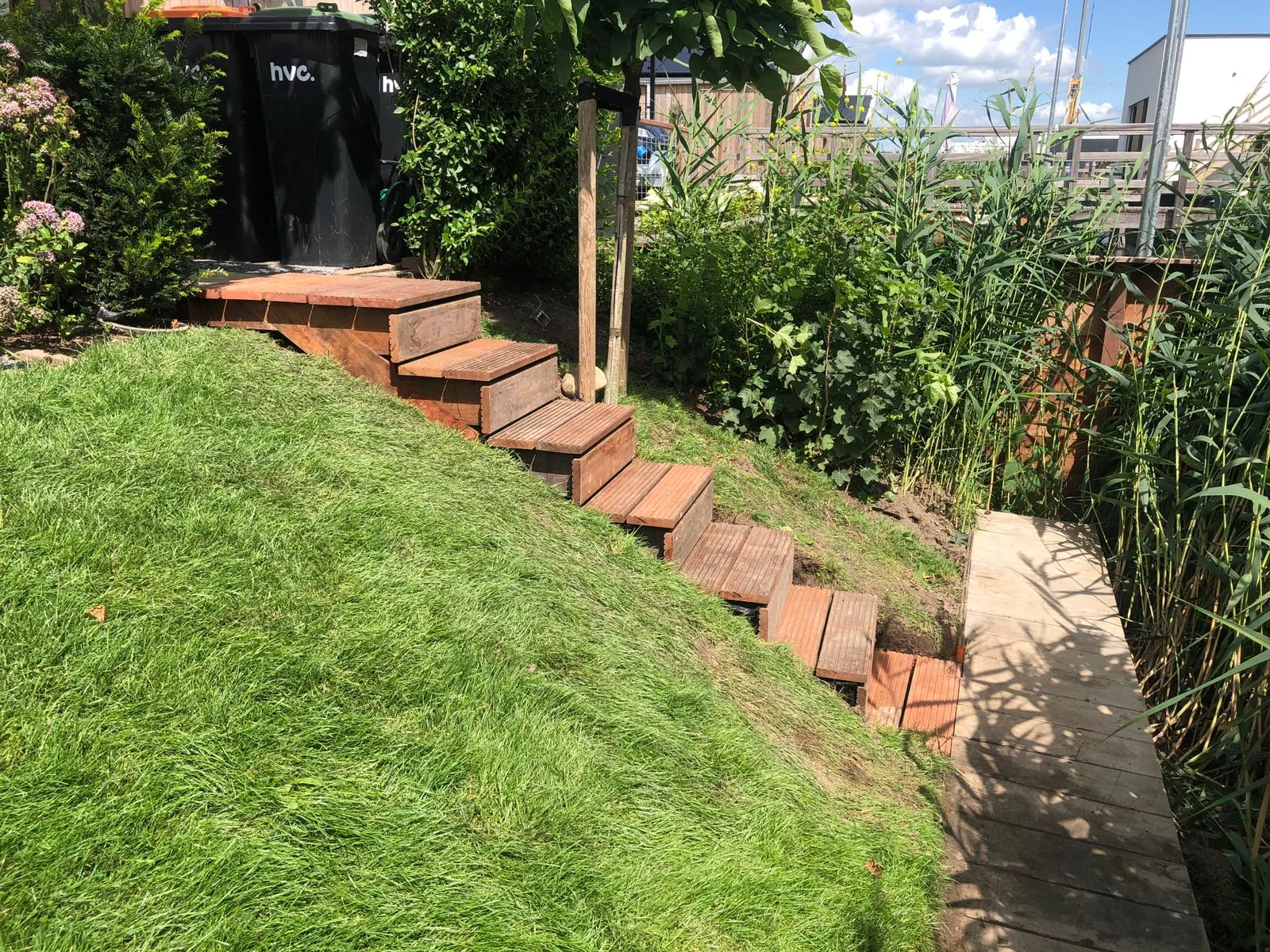 Aangelegde tuin met bestrating, gazon en houten plantenbakken