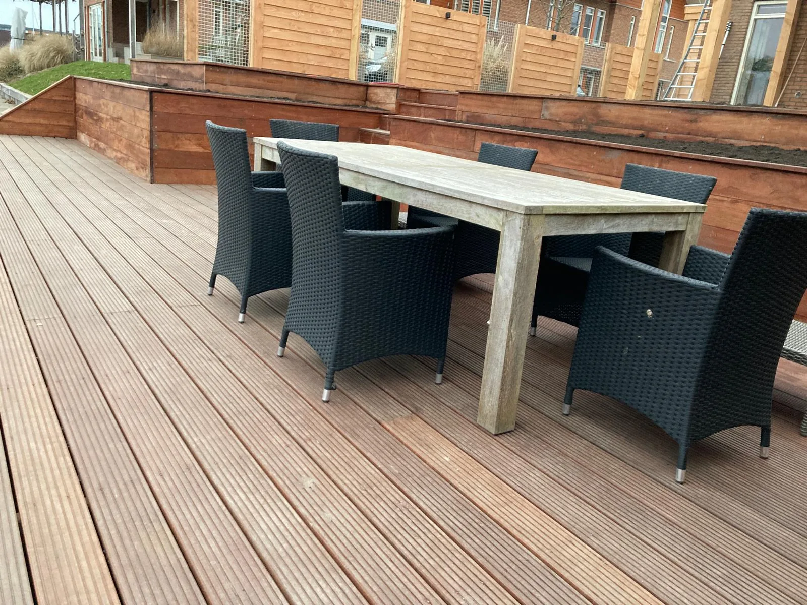 Ruim vlonderterras met eettafel en houten schutting